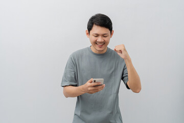 Happy expression of adult Asian man using mobile phone with casual t-shirt isolated on white background