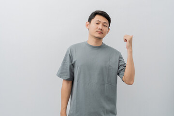 Sad and disappointed expression of adult Asian man pointing fingers with casual t-shirt isolated on white background