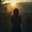 © StockUp - A woman stands alone, gazing toward a radiant sunset, embracing solitude and introspection in a serene landscape.