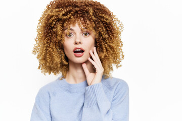 surprised woman with curly hair in light blue sweater, shocked expression, bright background, emotional reaction, cheerful mood, casual fashion sense, beauty and hairstyle concept