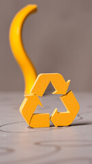 Poster - yellow cardboard recycling symbol on a gray surface