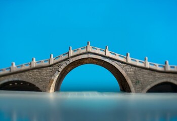 Aufkleber - A stone arch bridge over a calm body of water.