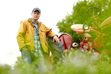 Tractor, farm and portrait of man with confidence, agro industry or small business owner at harvest. Agriculture, sustainability and farmer in field with pride, green plants and truck in countryside