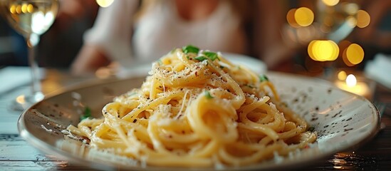 Canvas Print - Closeup of a plate of creamy pasta with a glass of wine in the background, ready to be served.