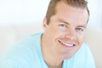 Excited, relax and portrait of man in home with positive attitude, chilling or resting in living room. Happy, calm and face of person from Germany with confidence and pride in lounge at apartment.