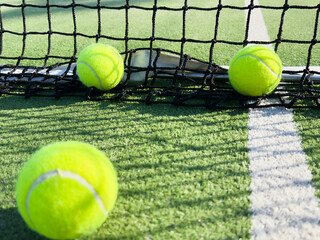  paddle tennis balls next to the net of a paddle tennis court