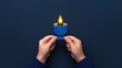 © KN Studio - Hanukkah Celebration: Child's Hands Holding a Blue Menorah with a Lit Candle