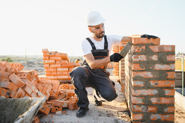 Construction worker man in work clothes and a construction helmet. Portrait of positive male builder in hardhat working at construction site