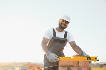 Indian Construction worker man in work clothes and a construction helmet. Portrait of positive male builder in hardhat working at construction site