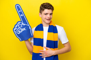 Teenager sports fan man isolated on yellow background smiling a lot