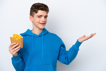 Teenager Russian man holding fried potatoes isolated on white background extending hands to the side for inviting to come