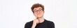 © yj - A happy young man wearing a glasses, with his index finger gently placed against his cheek, appearing to be in a thoughtful or curious pose isolated on white background.