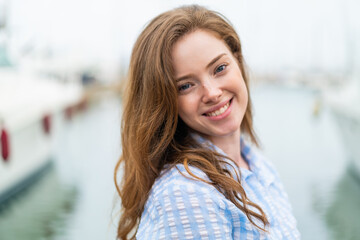 Wall Mural - Young redhead woman at outdoors With happy expression