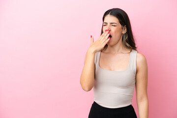 Young Italian woman isolated on pink background yawning and covering wide open mouth with hand