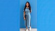© Tilak - Confident Female Student or Professional Holding Book Against Blue Wall