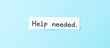© Rysak - white paper note with the words help needed on a blue background