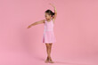 © New Africa - Little ballerina practicing dance moves on pink background