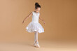 © New Africa - Little ballerina practicing dance moves on beige background