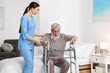 © New Africa - Nurse helping senior man with walking frame in clinic