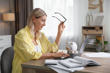 Budget planning. Woman using laptop at table indoors