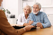© New Africa - Pension plan. Senior couple consulting with insurance agent at wooden table indoors