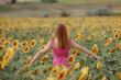 © TS-photo - A long-haired girl in a pink dress walks through a sunflower field. The concept of vegetable oil or good harvest of sunflower seeds. The girl straightens her brown hair in windy weather.