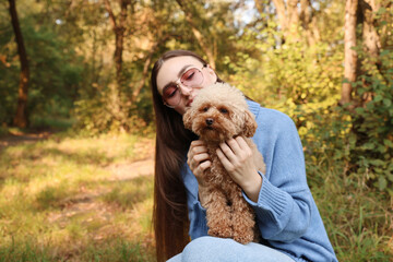 Wall Mural - Woman with cute dog in autumn park. Space for text