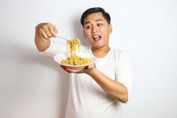 Adult Asian man showing surprised expression while eating noodle