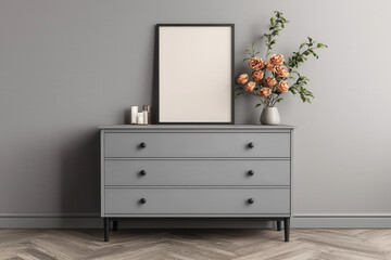 Aufkleber - A minimalist gray dresser under a blank frame, adorned with a floral arrangement, set against a muted wall and patterned floor.