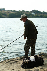 Wall Mural - Fisherman with rod fishing near lake at summer, back view