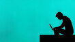© Sabbir - A silhouette of a man casually leaning over a laptop on a coffee table against a bright turquoise background.