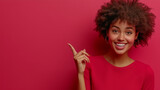 Kobieta o ciemnej karnacji z afro uśmiecha się do obiektywu. Wskazuje palcem w bok, sugerując miejsce na Twoją ofertę reklamową.