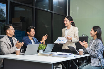 Asian businessman showing hand and smiling young team of colleagues making good business discussion in modern coworking office concept teamwork people