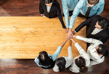 Multiracial business people make synergy hand stack together in meeting room as cooperation or team building for corporate employee in workplace. Panorama top view. Meticulous