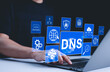 © Supatman - DNS domain name system and web server network system concept. A person uses a laptop, with DNS and web network icons representing domain name system, cybersecurity, and global internet connections.