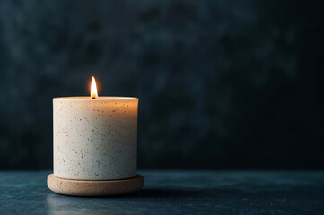 Aufkleber - White candle burning on a dark surface with a dark blurry background providing copy space