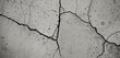 © CS - A black and white image captures a cracked concrete surface with numerous cracks, some of which are filled with water, creating a dynamic and textured scene