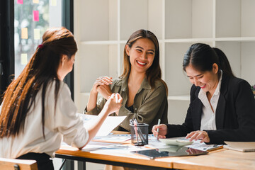 Collaborative women engaged in lively discussion, sharing ideas and laughter in modern office setting. Their expressions reflect joy and teamwork, creating positive work atmosphere