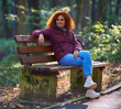 © Xalanx - Redhead woman sitting on the bench in a park