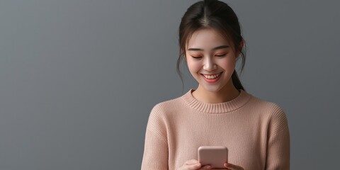 young smiling woman using mobile phone against gray background