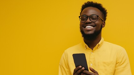 young smiling guy using mobile phone against yellow background