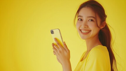 young smiling woman using mobile phone against yellow background