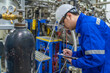 © reewungjunerr - Asian engineer working at Operating hall,Thailand people wear helmet  work,He worked with diligence and patience,she checked the valve regulator at the hydrogen tank.