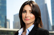 © Minerva Studio - Businesswoman smiling with city skyline in background