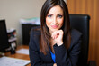 © Minerva Studio - Businesswoman smiling while sitting at desk in office