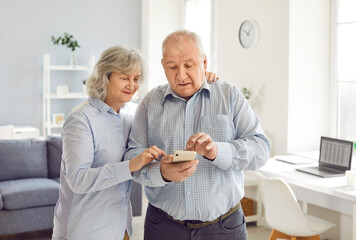 Senior couple, retired old man, woman elderly peple using together mobile phone text, communicate with doctor, children, asking service help. Grandparents at home, answering phone call, conversation