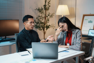 Two business partners experiencing conflict and disagreement while working late in the office