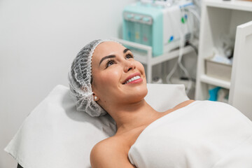 Young woman smiling and relaxing lying on the bed in a medical spa center