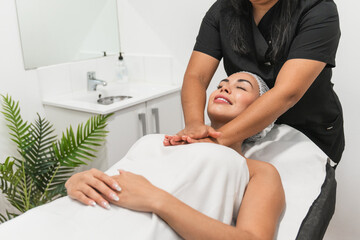 Beautician giving neck massage to beautiful woman in beauty salon