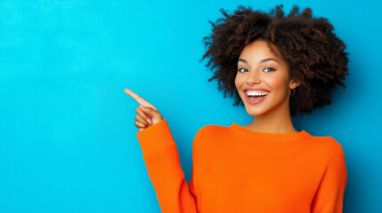 Smiling woman in orange sweater pointing against blue background